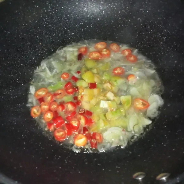 Masukkan irisan cabai rawit, cabai merah, dan tomat, kemudian tumis sebentar sampai layu, lalu tuang air.