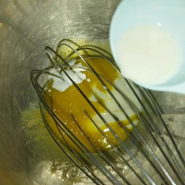 Siapkan wadah, masukkan kuning telur, aduk rata, lalu tambahkan vanilli bubuk dan susu cair, aduk rata.