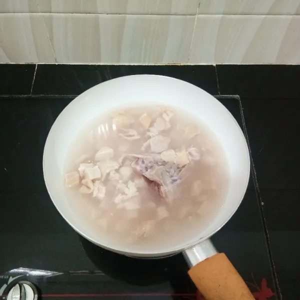 Potong dadu dada ayam lalu rebus bersama tulangnya dengan air secukupnya hingga mendidih lalu tiriskan ayam dan buang air rebusannya.