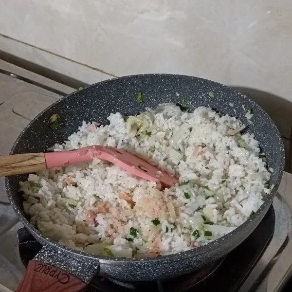 Masukkan nasi, aduk rata kemudian tambahkan garam, kaldu bubuk dan saos tiram. Aduk terus sampai bumbu meresap kurang lebih 4 menit.