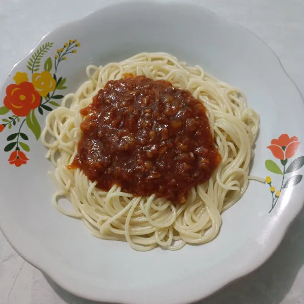 Tata pasta spaghetti di atas piring, kemudian tuang saos bolognese di atasnya.