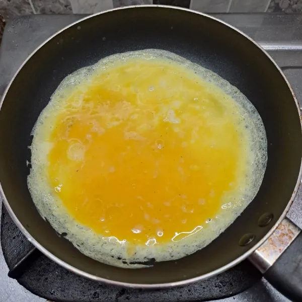 Panaskan teflon dengan api kecil dan sedikit minyak goreng. Tuang adonan telur, putar teflon agar adonan rata.