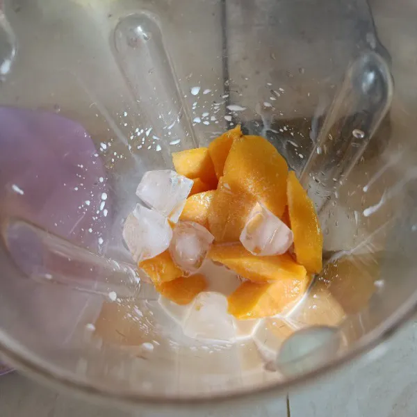 Potong-potong mangga kemudian campurkan dengan susu cair, gula dan es batu.