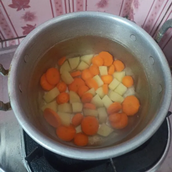 Rebus air hingga mendidih, setelah mendidih, masukkan kentang dan wortel, rebus hingga setengah matang.