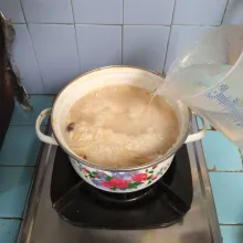 Tambahkan air panas, aduk rata. Masak hingga beras lunak. Gunakan api kecil.