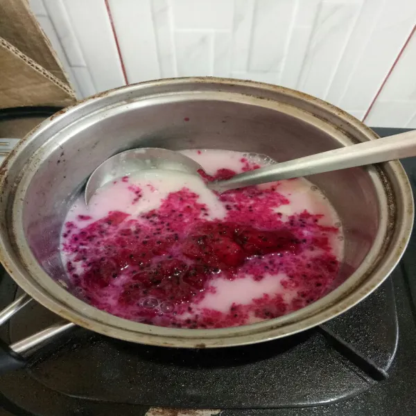 Sisa agar-agarnya panaskan kembali tambahkan buah naga aduk terus masak sebentar hingga mendidih sambil di aduk terus matikan kompor.