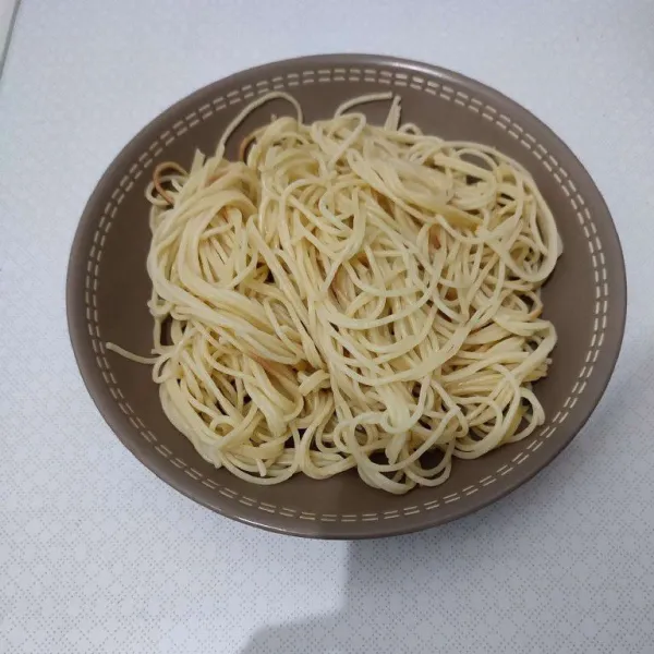 Salin spaghetti yang sudah direbus ke atas piring saji.