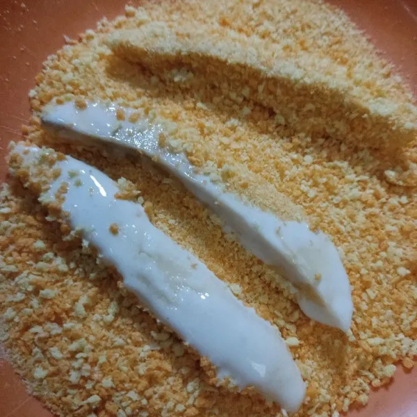 Gulingkan pisang yang telah di balut adonan tepung ke tepung roti hingga terbalur. Lakukan hingga selesai.