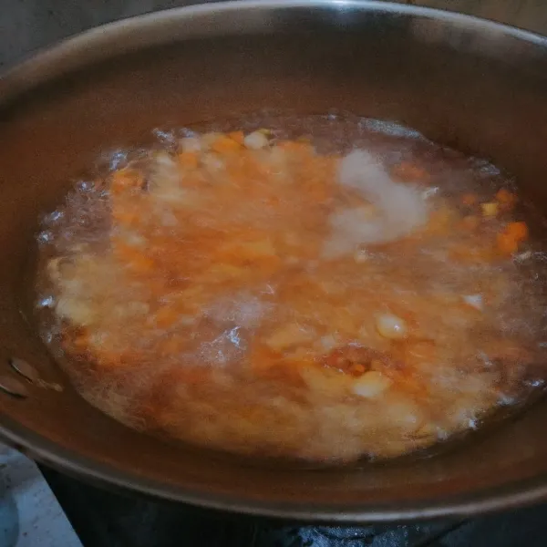 Panaskan air hingga mendidih lalu masukkan wortel dan jagung terlebih dahulu.