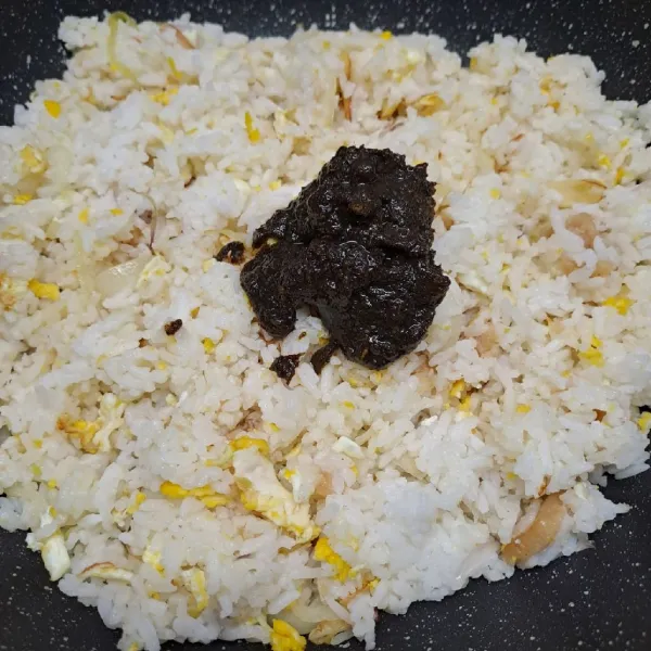 Masukkan nasi dan bumbu rawon. Bumbui kaldu jamur dan garam, aduk rata sambil koreksi rasa sesuai selera.