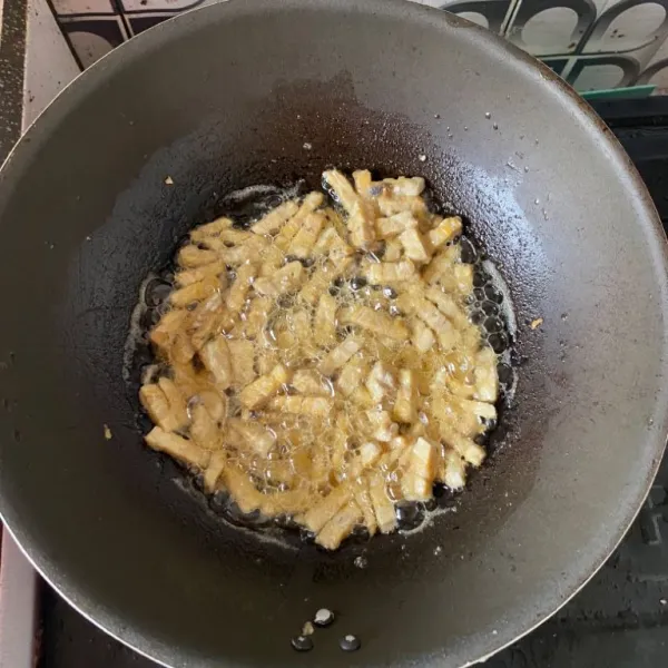 Goreng tempe yang sudah dipotong-potong dengan minyak panas. Lalu, tiriskan.