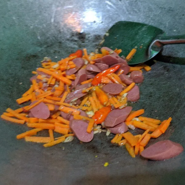 Masukkan wortel dan sosis, tumis kembali hingga wortel layu.