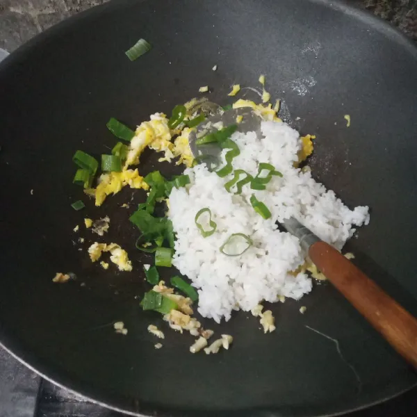 Masukkan nasi putih dan daun bawang. Aduk rata.