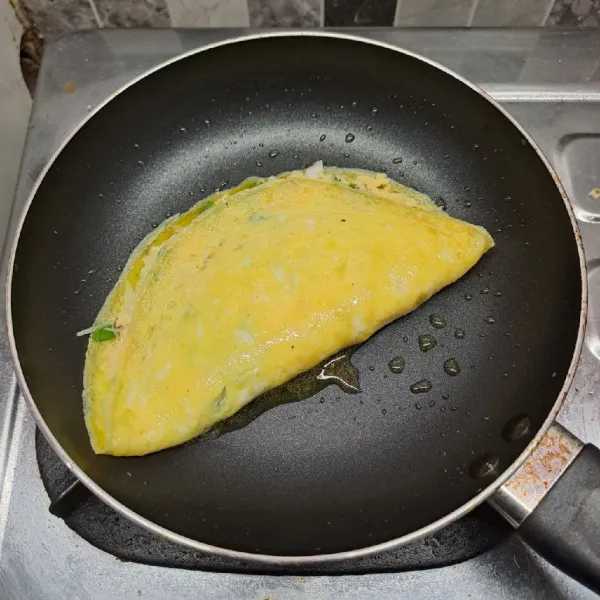 Lipat telur, tekan-tekan bagian pinggir dengan spatula agar menempel rapat. Balik telur jika sisi bawah sudah kecoklatan. Masak sampai matang. Angkat dan tiriskan. Potong telur 4 bagian, beri toping saos tomat dan mayonnaise. Sajikan.