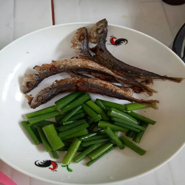 Cuci bersih bunga bawang lalu iris. Goreng ikan gambolo hingga berkulit. Sisihkan.