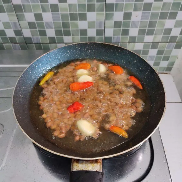 Goreng kacang tanah, cabe dan bawang putih secara bersamaan hingga matang, jangan sampai gosong, kemudian tiriskan. Biarkan sebentar hingga dingin.