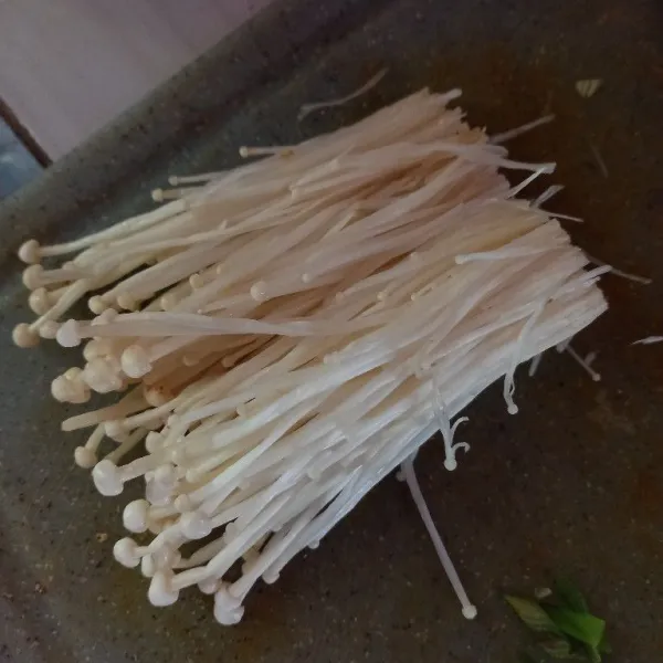 Bersihkan jamur enoki, buang akarnya, lalu cuci bersih.