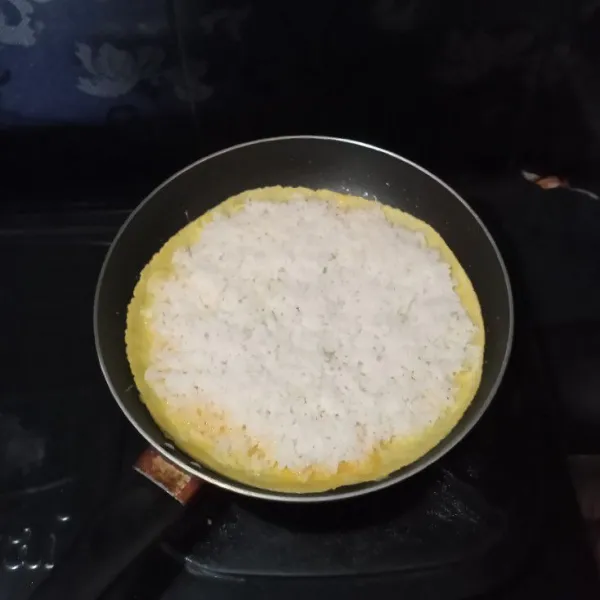 Jangan tunggu telur matang, saat masih basah masukkan nasi, ratakan.