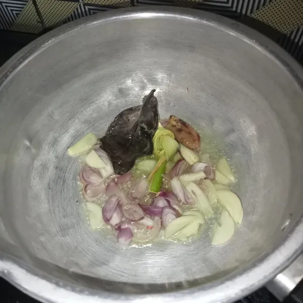 Tumis bawang merah, bawang putih, serai, jahe, dan daun salam sampai harum.