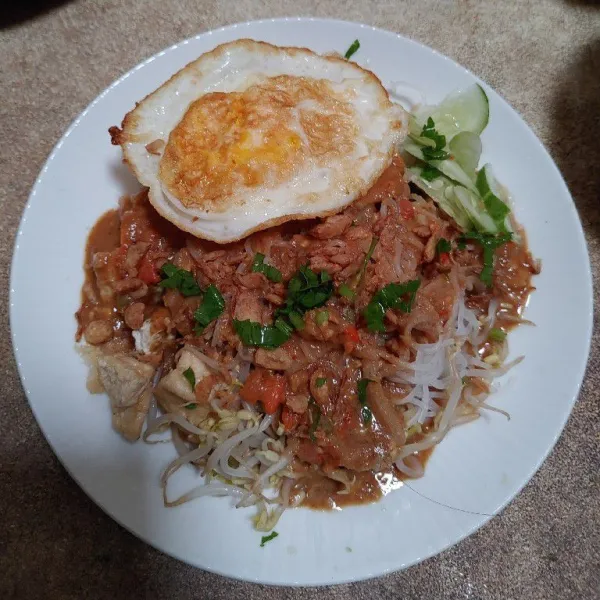 Terakhir siram dengan bumbu kacang, tambahkan topping telur ceplok, irisan timun dan beri taburan bawang goreng dan seledri, terakhir kerupuk. Selamat mencoba.