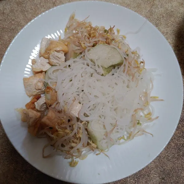 Di dalam piring terpisah, tambahkan isian lontong, tahu, sayur tauge rebus dan soun.