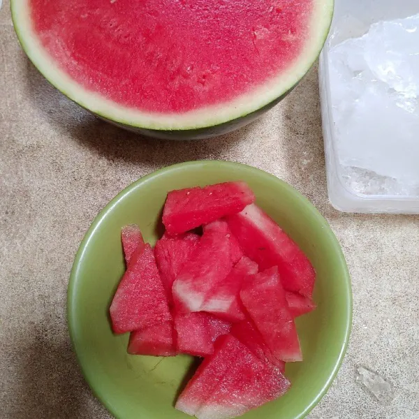 Potong semangka tanpa biji, lalu kupas kulitnya.