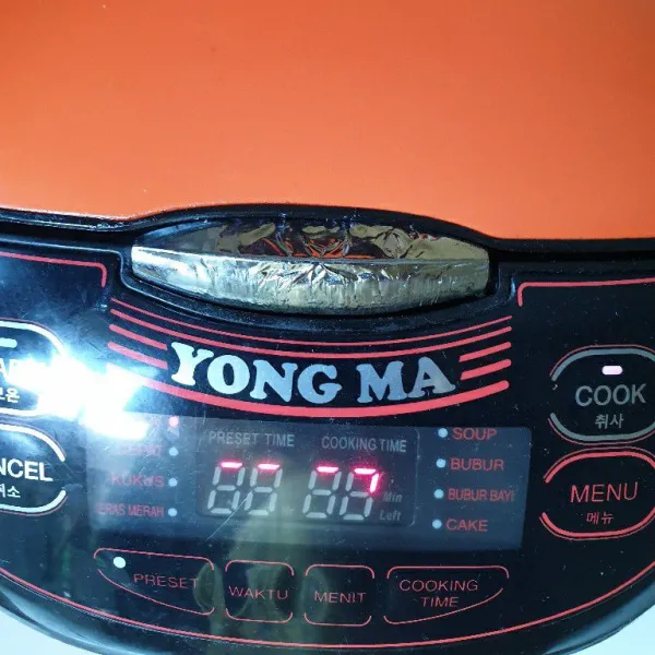 Magic com dalam posisi menyalakan dengan nasi liwet yang sedang dimasak