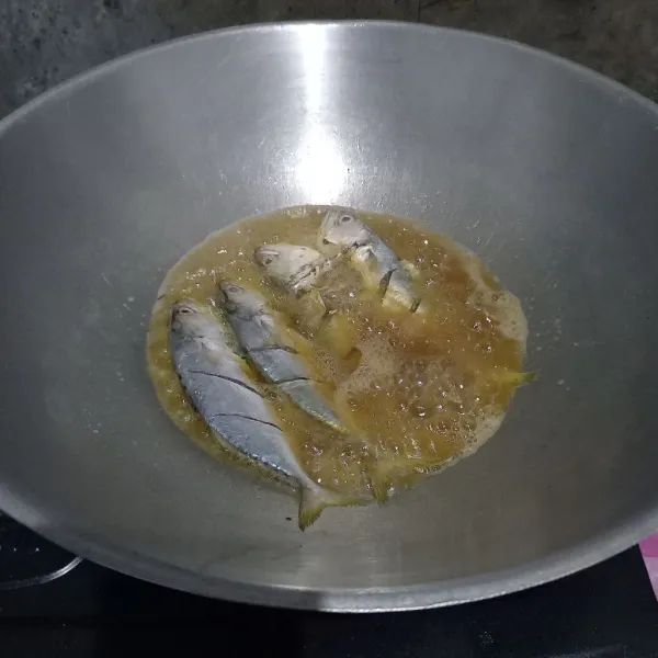 Panaskan minyak goreng. Masukkan satu sendok tepung terigu ke dalam minyak goreng dan aduk. Kemudian masukkan ikan.