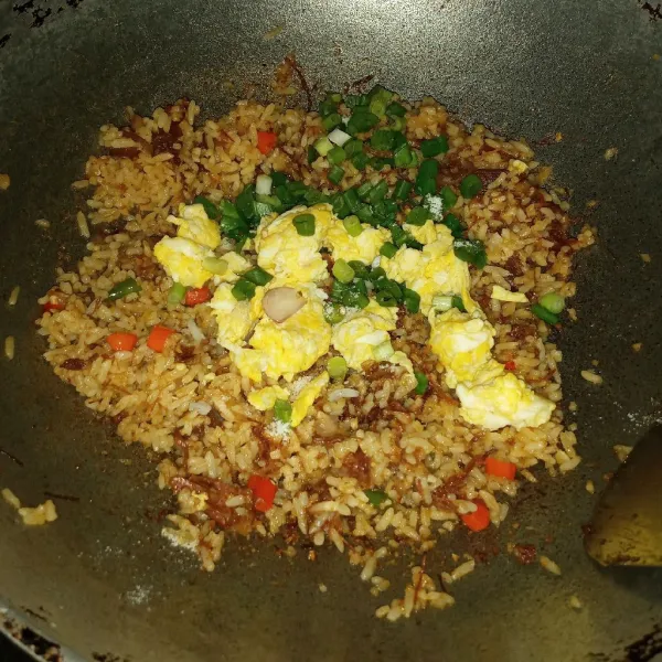 Masukkan orak arik telur dan gaun bawang. Tambahkan garam jika dibutuhkan. Aduk dan masak sampai nasi goreng matang (teksturnya jadi kering seperti nasi goreng pada umumnya), cek rasa kembali lalu matikan api.