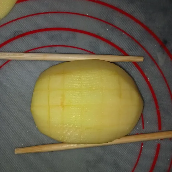 Potong kentang menjadi dua kemudian ambil satu bagian kentang lalu tekan dengan sumpit sisi kanan dan kiri kerat kentang jangan sampai terputus (fungsi sumpit membantu menahan kentang supaya kentang tidak mudah putus).