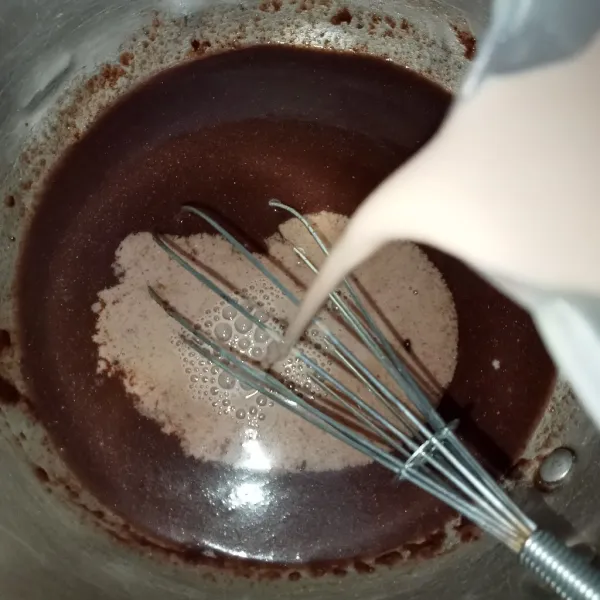 Tuang susu cair sedikit demi sedikit sambil diaduk hingga tercampur rata lalu masukkan pasta coklat, aduk rata kembali.