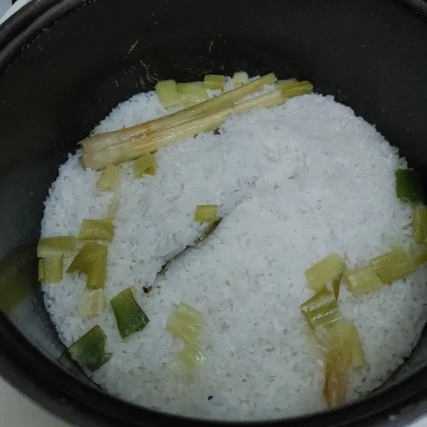Kemudian tambahkan serai, daun salam, daun bawang, garam dan kaldu bubuk dan minyak goreng. Masak nasi menggunakan rice cooker dan masak sampai matang.