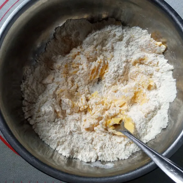 Campur semua bahan kulit pai kecuali air, aduk menggunakan garpu sampai berbulir.