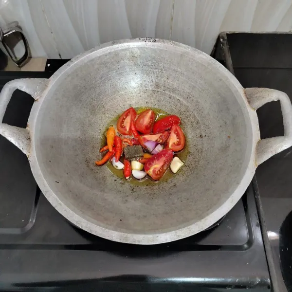 Panaskan kembali minyak bekas menggoreng ikan tadi. Masukkan cabai, bawang merah, bawang putih, tomat dan terasi. Lalu goreng hingga layu. Angkat.