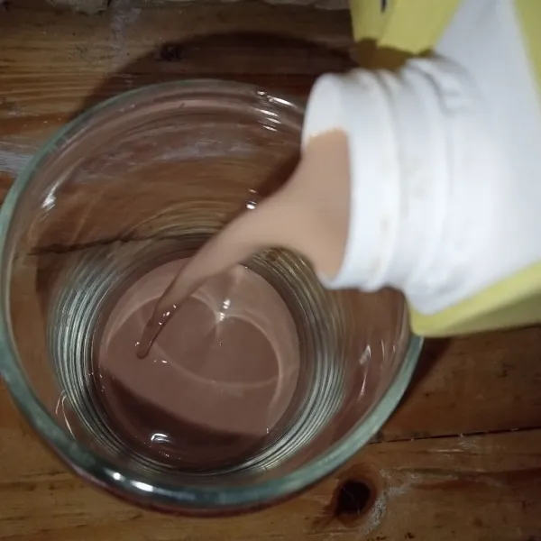 Tuang susu cokelat ke dalam gelas.