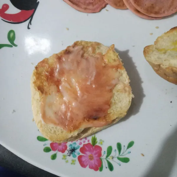 Panggang roti bun sebentar lalu oles dengan saus tomat dan mayonaise.