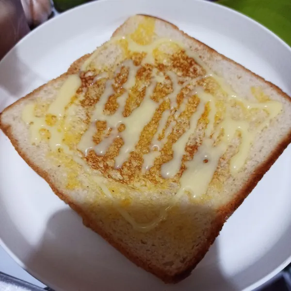 Letakkan roti di piring, beri 1 sdt kental manis putih.