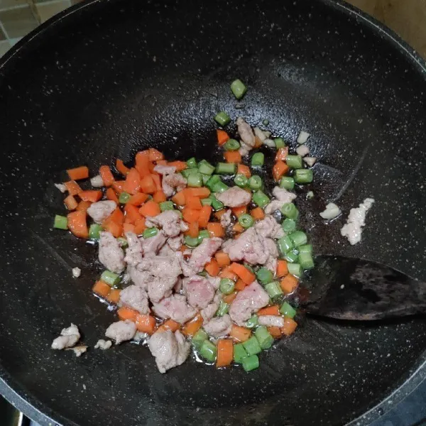 Tumis bawang putih dan daging ayam hingga matang, lalu masukkan sayur wortel dan buncis. Aduk rata, tambahkan sedikit air agar sayuran cepat empuk.