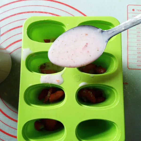 Masukkan potongan strawberry yang sudah layu beserta cairannya ke lubang cetakan es loli.
