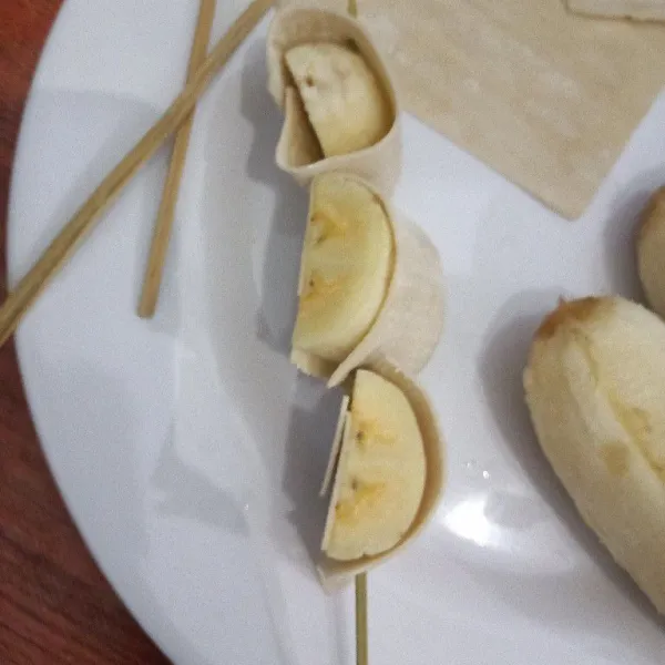 Tusuk potongan pangsit pisang dengan tusukan sate.