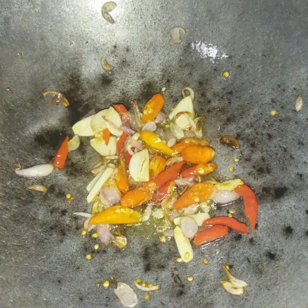 Panaskan minyak goreng, tumis bawang merah dan bawang putih hingga harum, lalu masukkan cabe rawit dan cabe merah, tumis hingga layu.