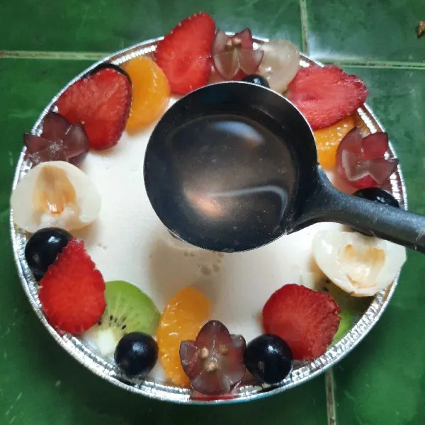 Tuangkan jelly di atas puding yang sudah dihias buah.