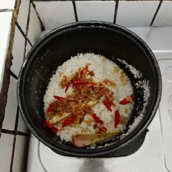 Masukkan beras dan semua bahan tumisan beserta minyaknya ke dalam rice cooker. Tambahkan air, garam, gula pasir dan lada bubuk, aduk dan tes rasa.