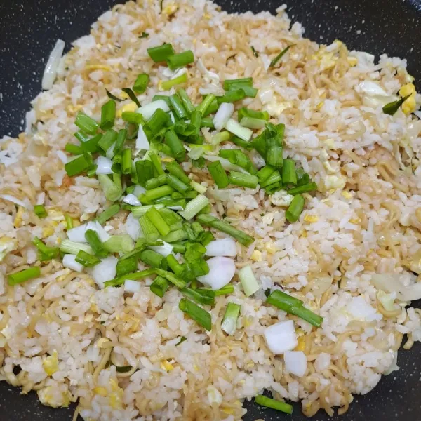 Masukkan irisan daun bawang, aduk rata. Masak sampai daun bawang layu. Angkat dan sajikan nasi goreng dengan taburan bawang merah goreng.