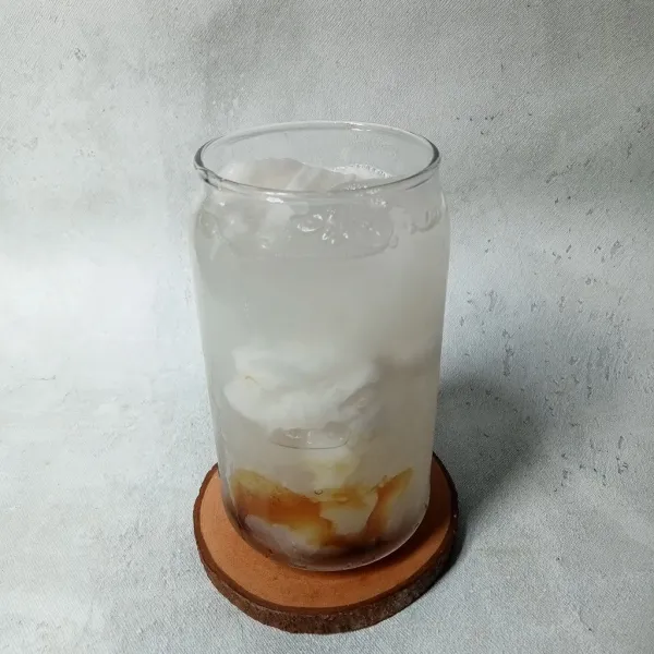 Tuang air kelapa muda sampai gelas hampir penuh.