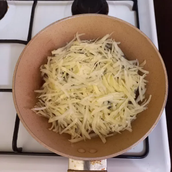 Panaskan minyak tata kentang parut di atas wajan masak kentang hingga setengah matang