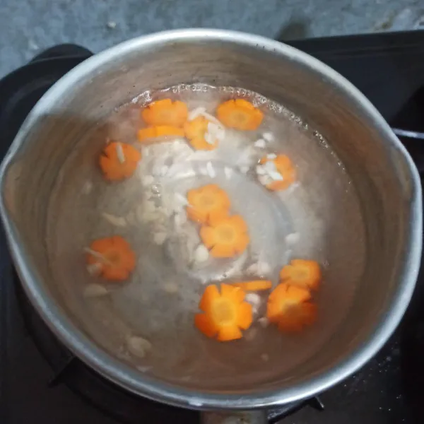Didihkan air, setelah mendidih masukkan wortel dan bawang putih. Tunggu setengah matang.