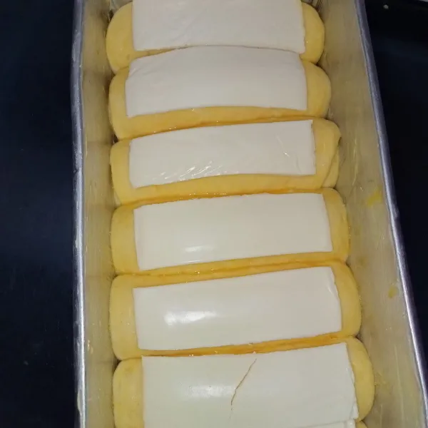 Tata didalam loyang yang sudah diolesi dengan margarin. Proofing selama 30 menit atau sampai mengembang dua kali lipat. Olesi dengan kuning telur kemudian letakkan keju slices diatasnya.