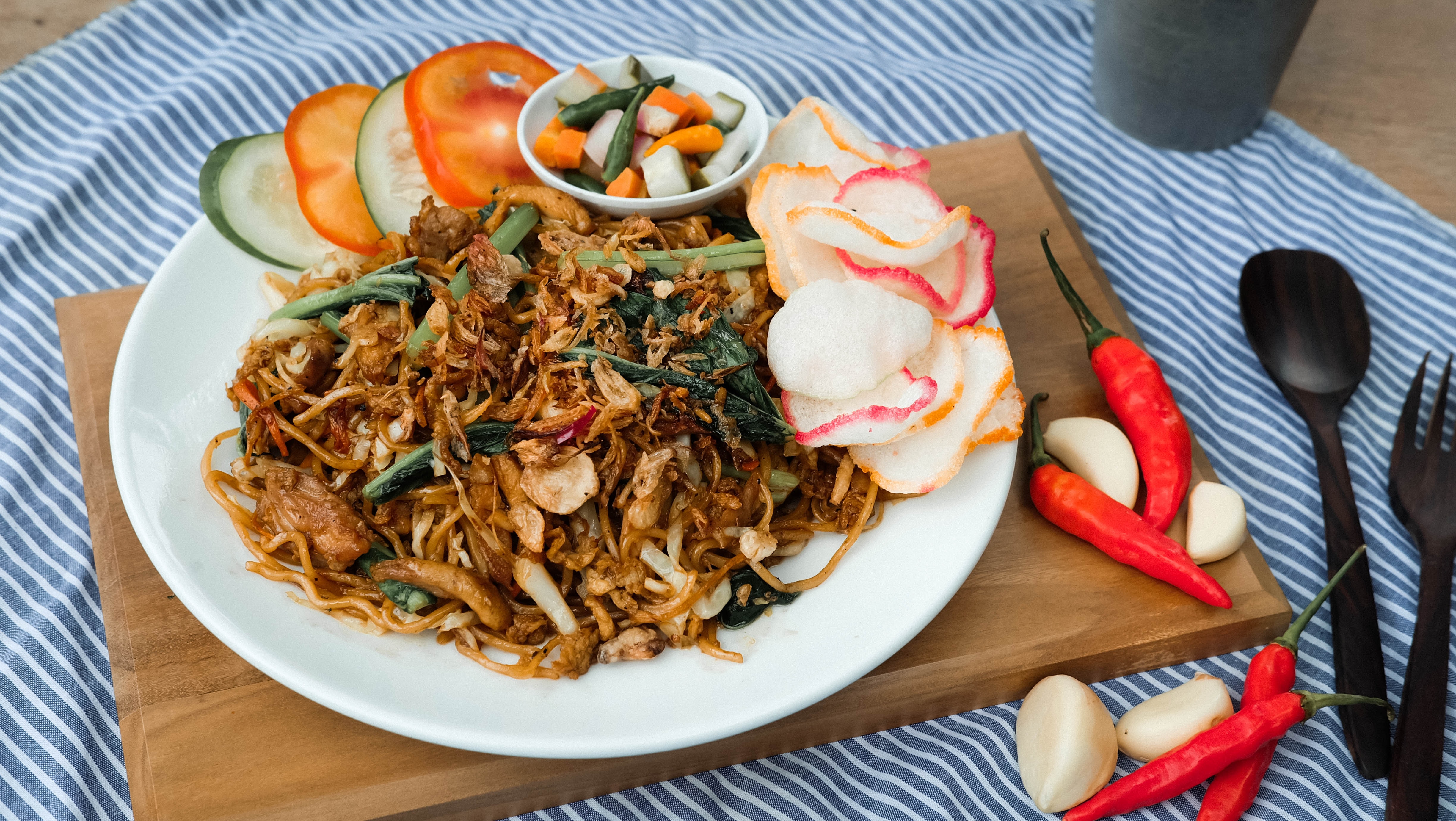 Mie goreng dengan acar, tomat, timun, dan kerupuk
