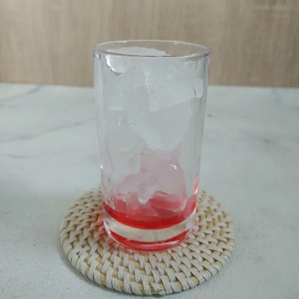 Didalam gelas tuang sirup cocopandan lalu tambahkan es batu.
